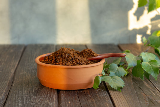 Chaga Pulver in einem Terracotta Gefäss auf einem Holztisch